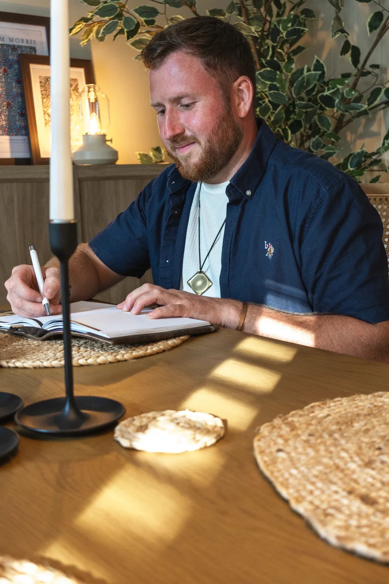 David Falconer writing in a notebook at a table